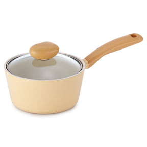 A small saucepan with a matte beige exterior, a matching beige handle, and a clear glass lid with a beige knob, shown on a plain white background.