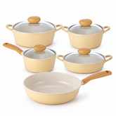 A 5-piece non-stick cookware set in a warm cream-beige color with light brown wooden handles and knobs, including two pots with glass lids, two saucepans, and one deep saute pan, arranged on a white background.