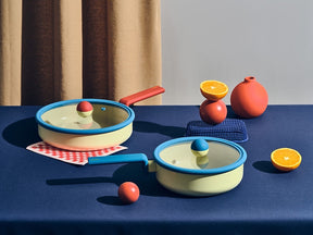 Neoflam Danish cookware set: a pastel yellow 20cm stockpot with blue rim and red/yellow knob, and a matching wok. Both have glass lids.